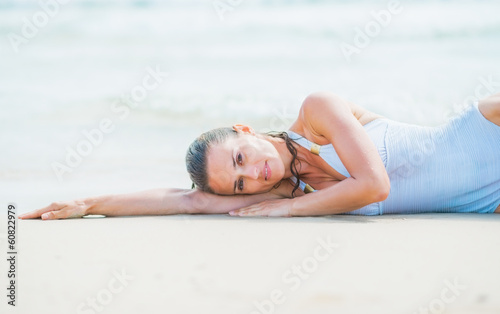 Young woman in swimsuit laying on sea coast