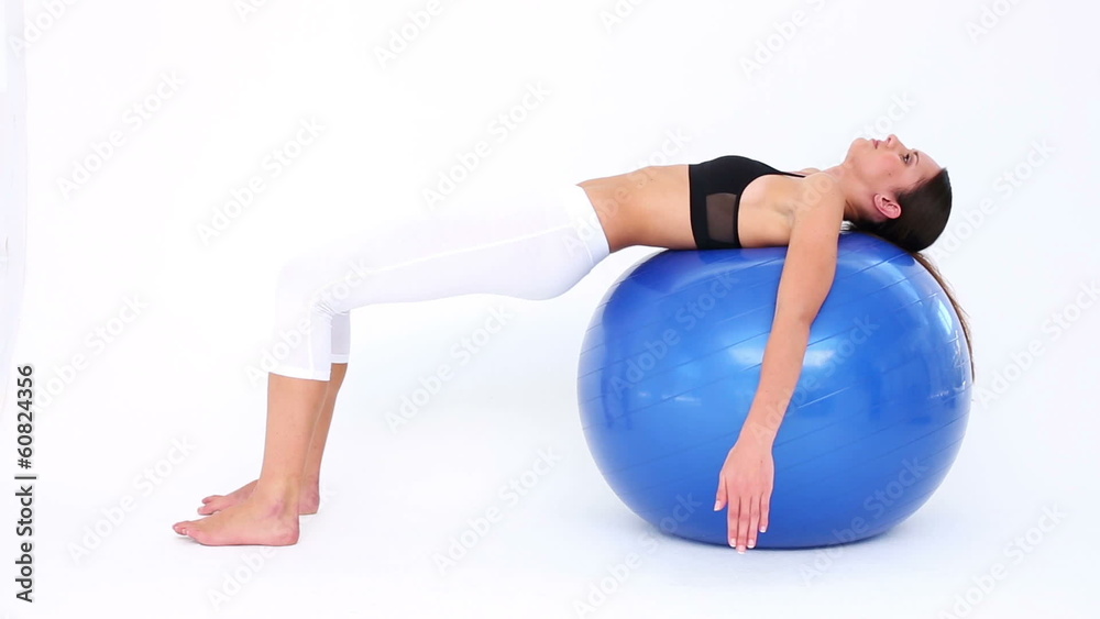 Fit model doing pelvic lifts on blue exercise ball Fit model doing pelvic lifts on blue exercise ball