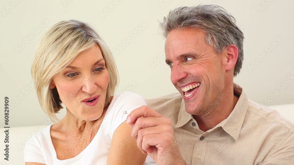 Man giving his wife a ring on the couch Man giving his wife a ring on the couch