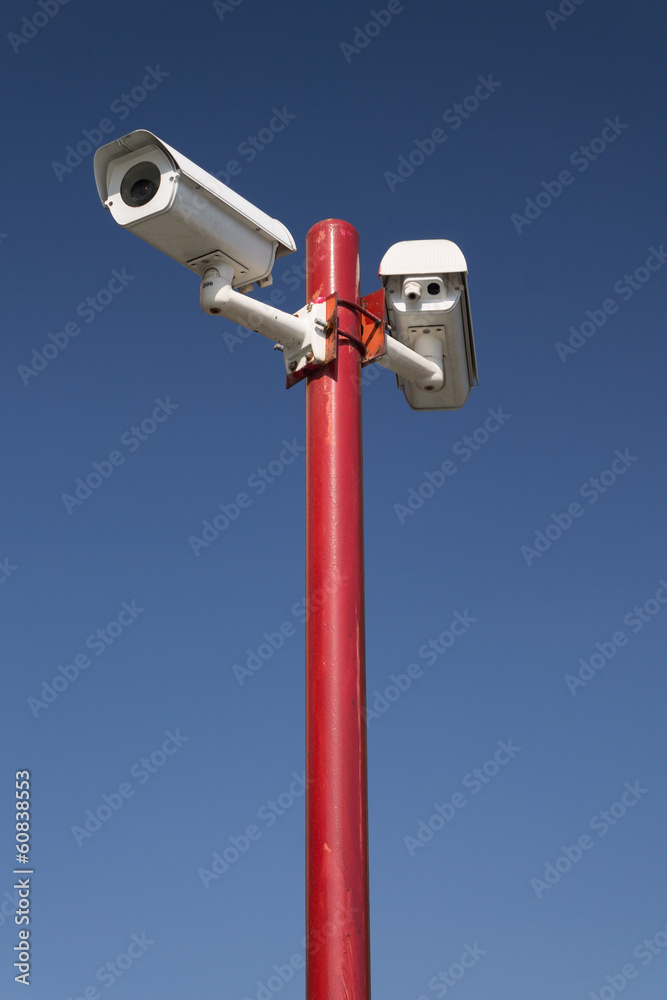 security camera on red pillar,blue isolated security camera on red pillar,blue isolated