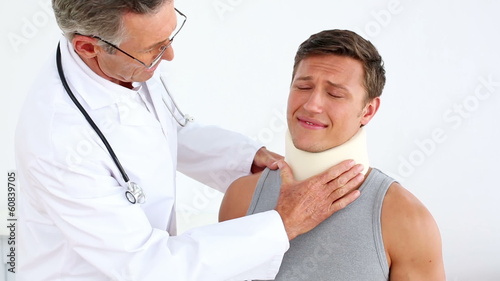 Sportsman in neck brace being checked by doctor