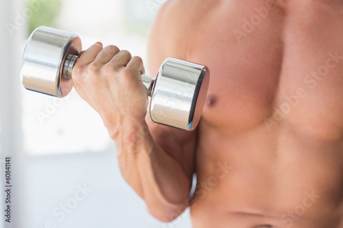 Mid section of a sporty young man with dumbbell