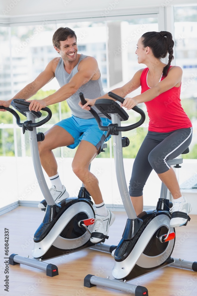 Smiling young couple working out at spinning class Smiling young couple working out at spinning class