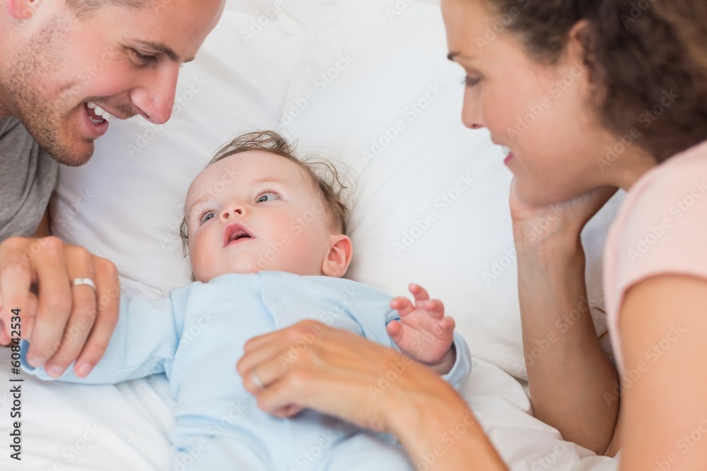 Parents looking at baby boy in bed