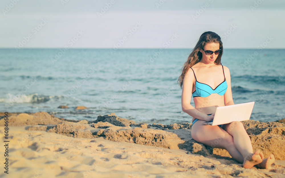 Woman with laptop working on the beach. Place for text. Woman with laptop working on the beach. Place for text.