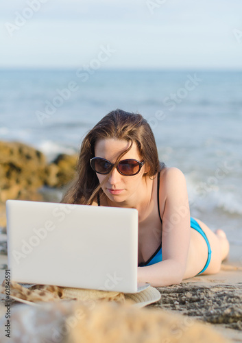 Woman with laptop working on the beach. Place for text.