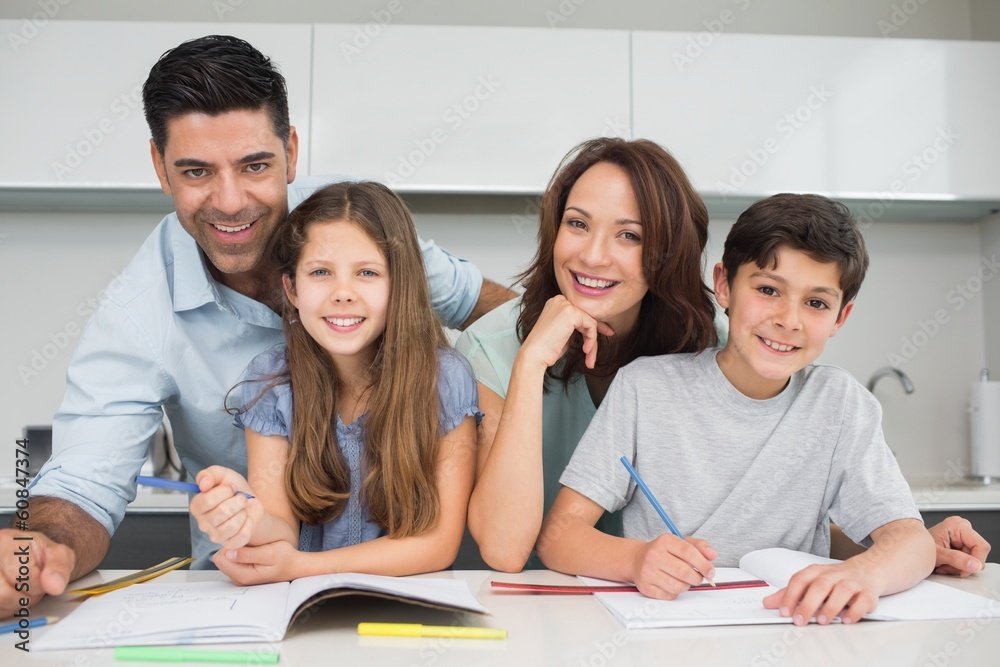 Smiling couple helping kids with homework at home Smiling couple helping kids with homework at home