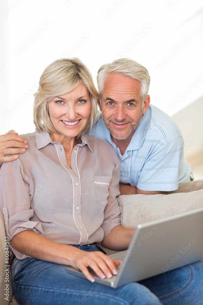Happy mature couple using laptop on sofa Happy mature couple using laptop on sofa