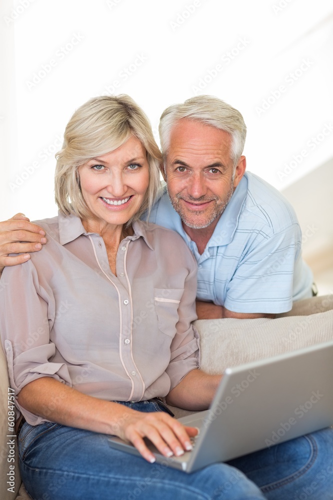 Happy mature couple using laptop on sofa