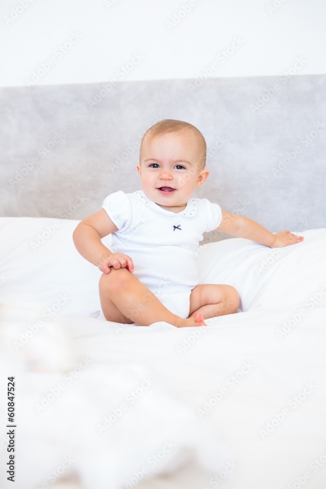 Full length portrait of cute baby sitting on bed