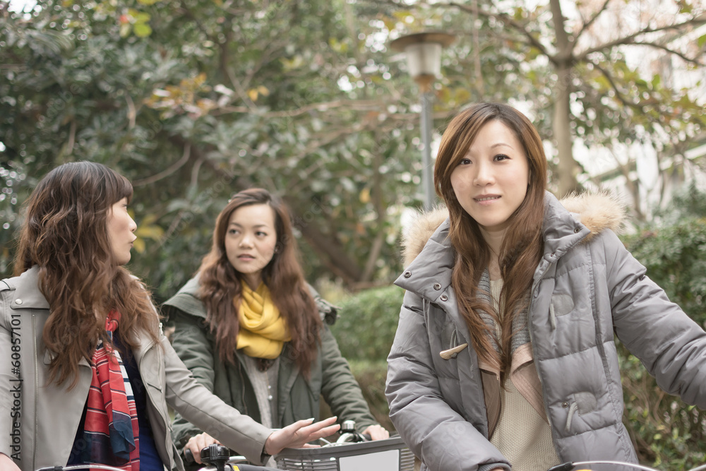 Young Asian woman riding bicycle with friends Young Asian woman riding bicycle with friends