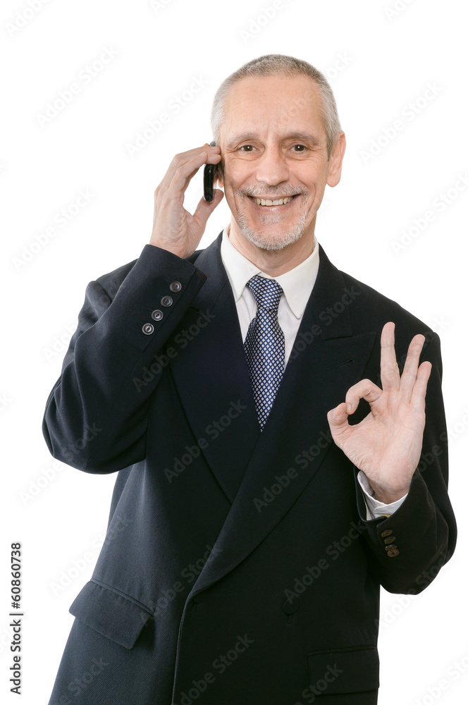 An amiable businessman smiling on mobile phone and showing the okay sign with the hand An amiable businessman smiling on mobile phone and showing the okay sign with the hand