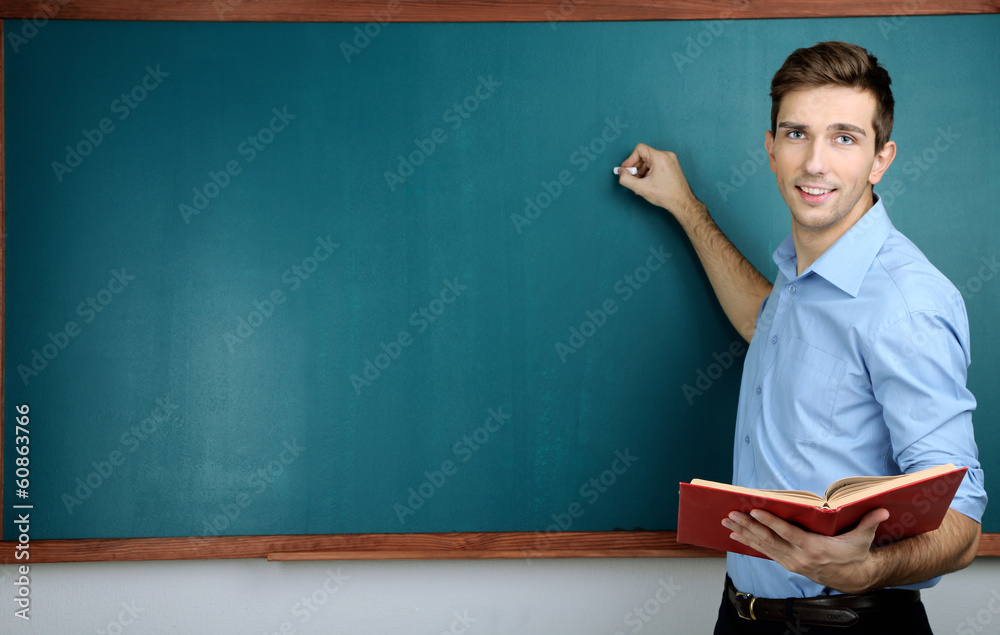 Young teacher near chalkboard in school classroom Young teacher near chalkboard in school classroom