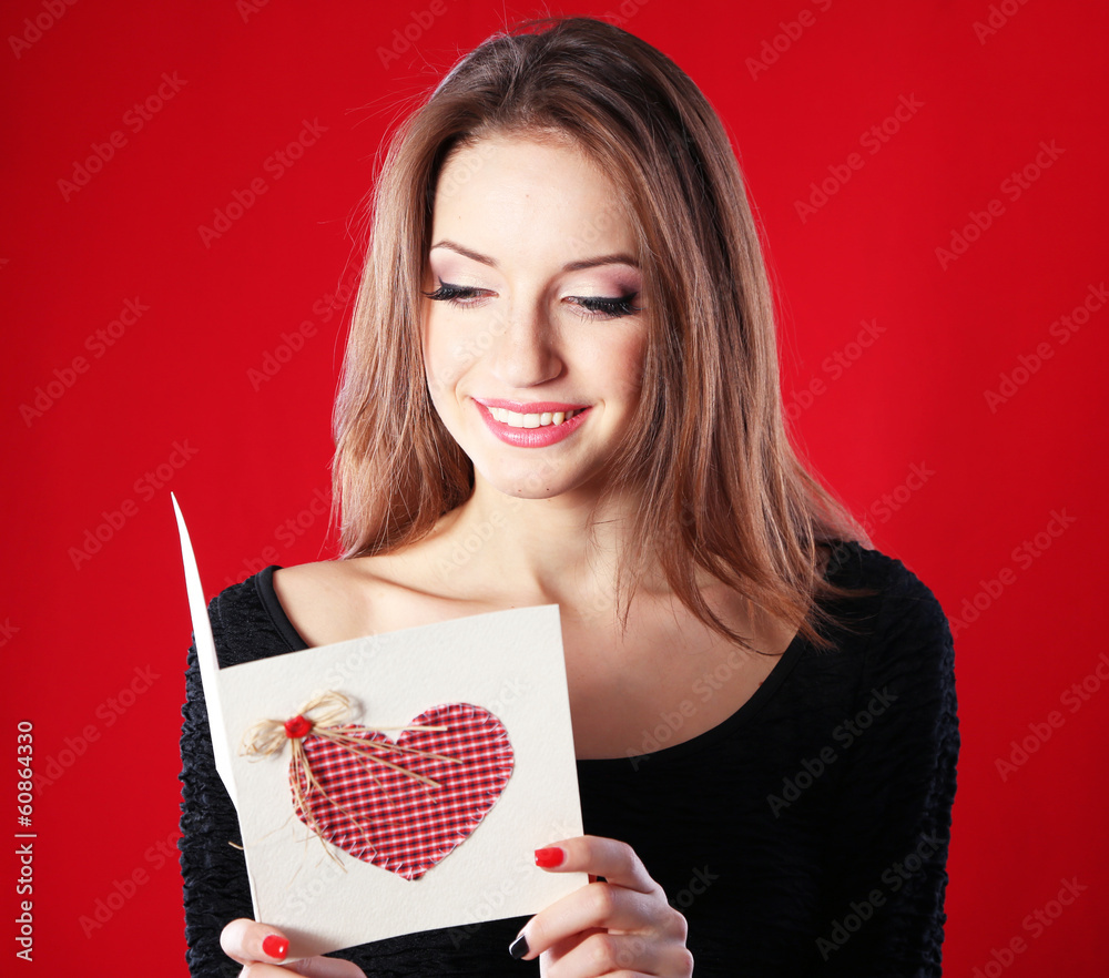 Attractive woman with postcard, on red background Attractive woman with postcard, on red background
