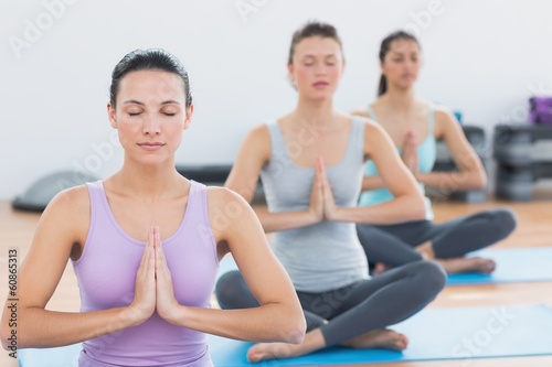 Women in Namaste position with eyes closed at fitness studio