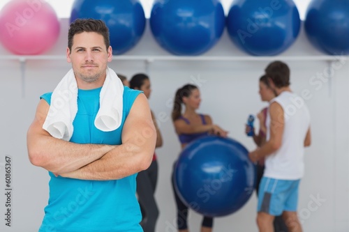 Fit man with friends in background at fitness studio