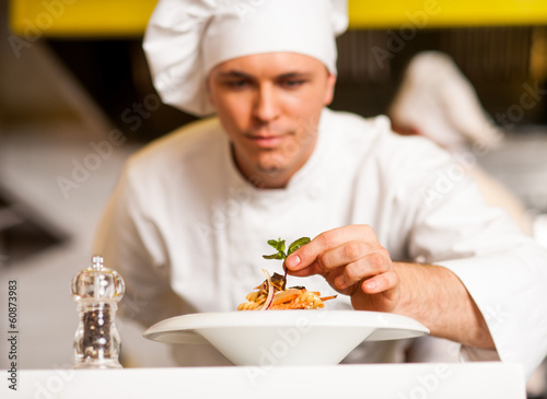 Chef decorating pasta salad with herbal leaves