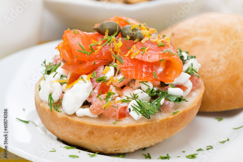bun with cottage cheese, herbs, tomato and salmon, close-up