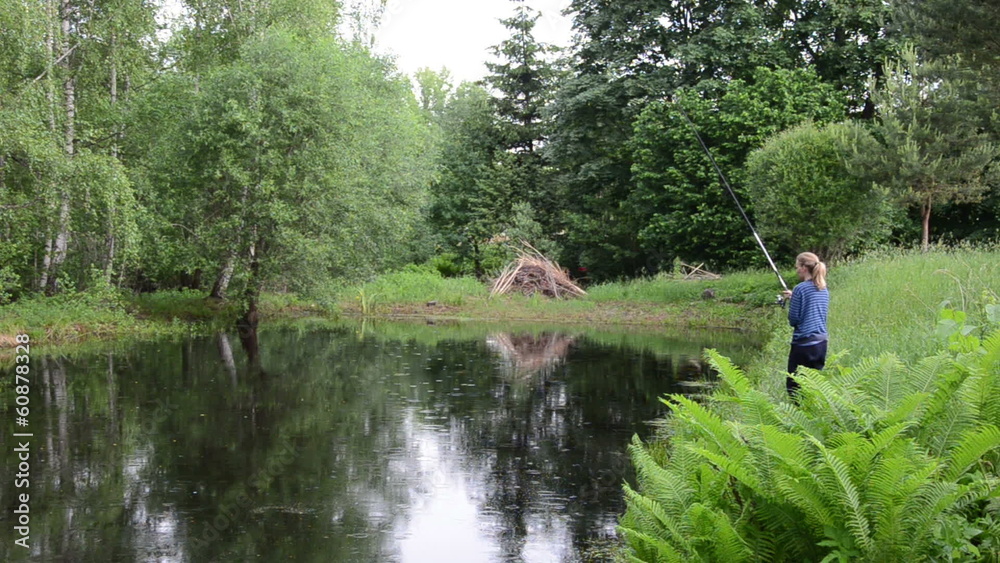 woman with blue sweater fishing rural pond in the rain woman with blue sweater fishing rural pond in the rain