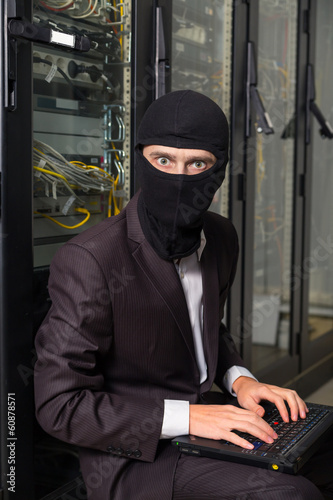 robber in black mask hack server room downloading data on laptop