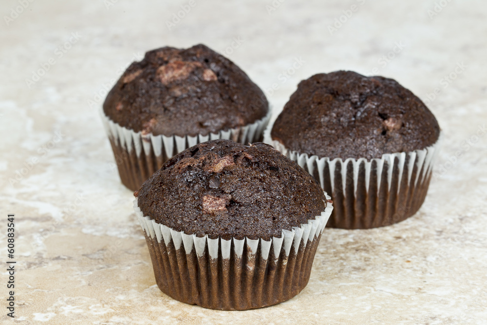 Delicious chocolate chip muffins standing on a tile background Delicious chocolate chip muffins standing on a tile background