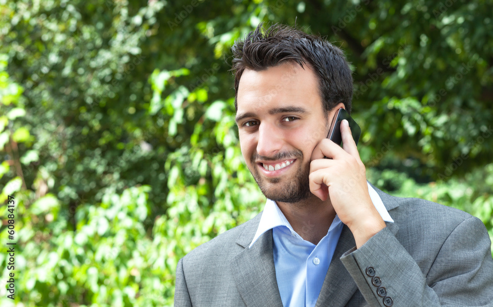 Attractive latin businessman on the phone in a park Attractive latin businessman on the phone in a park