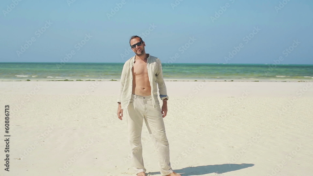 Portrait of young happy man standing on beautiful exotic beach Portrait of young happy man standing on beautiful exotic beach