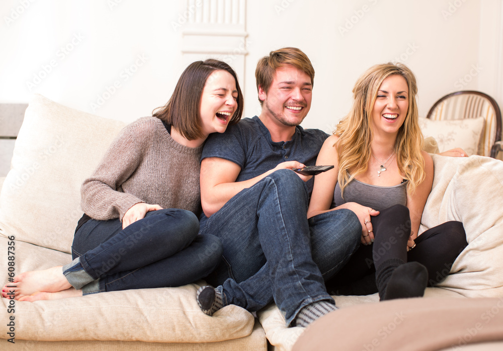 Three teenagers enjoy a funny television program