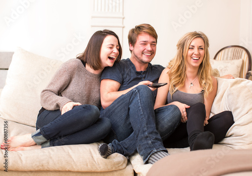 Three teenagers enjoy a funny television program