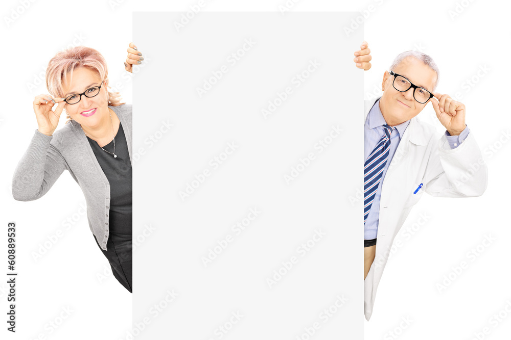 Middle aged woman and male doctor standing behind blank panel Middle aged woman and male doctor standing behind blank panel