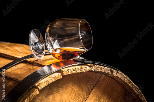 Glass of cognac on the old wooden barrel photo