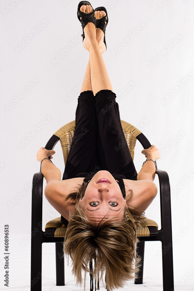 A young business woman is doing acrobatics on a chair