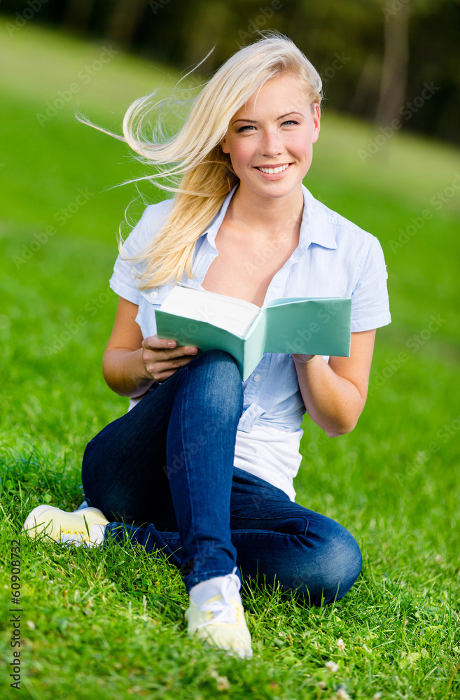 Girl reading book sits on the green grass in the park Girl reading book sits on the green grass in the park