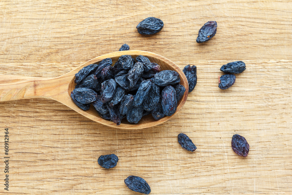 Wooden spoon with raisins on a wooden board Wooden spoon with raisins on a wooden board