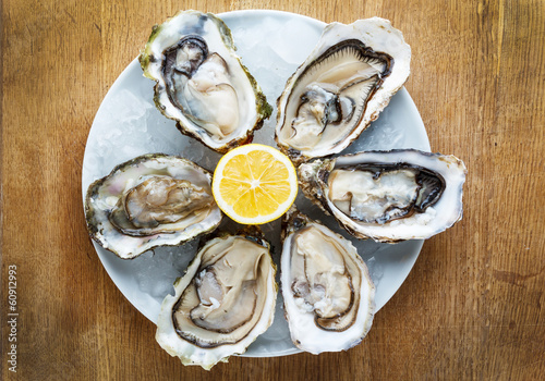Fresh oysters in a white plate with ice and lemon