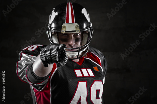 Portrait of american football player pointing at you.