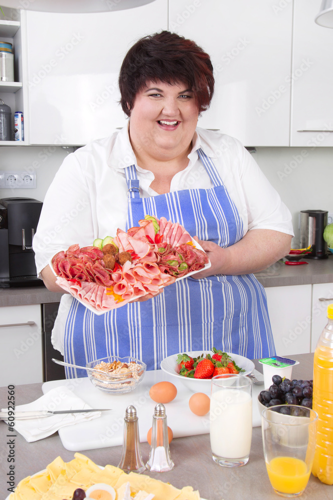 Mollige Frau mit Wurst in der Küche - ungesunde Ernährung