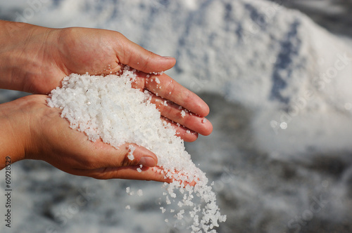 Hands full of salt with piles in the background