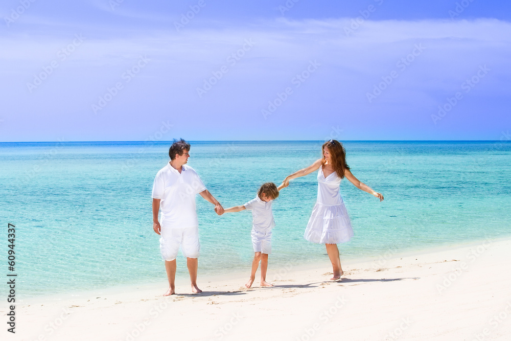 Happy family of three dancing on the beach