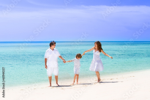 Happy family of three dancing on the beach