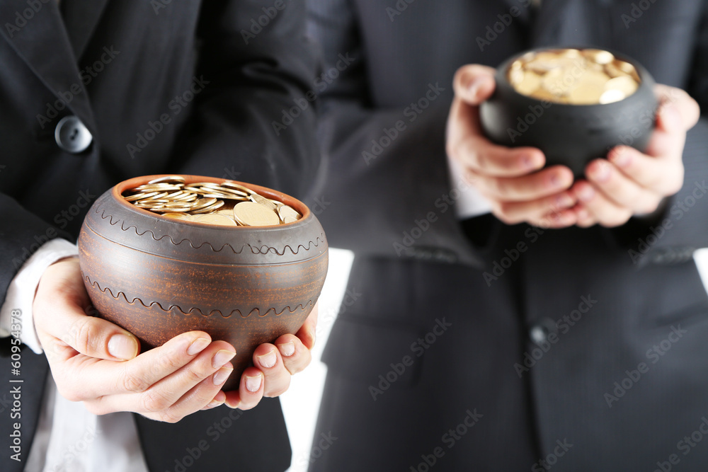 Two ceramic pots with golden coins in male and female hands, Two ceramic pots with golden coins in male and female hands,