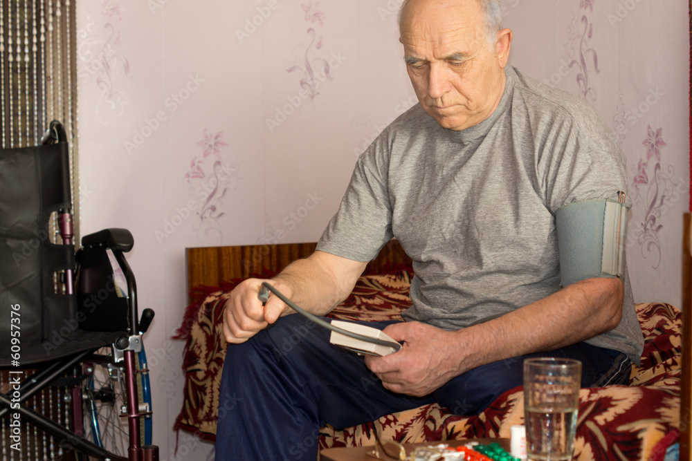 Senior disabled man taking his own blood pressure