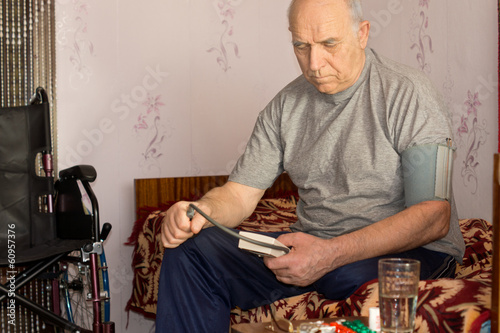 Obraz na płótnie Senior disabled man taking his own blood pressure w salonie