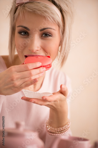 Young beautiful blond woman eating macaroon while having tea-par
