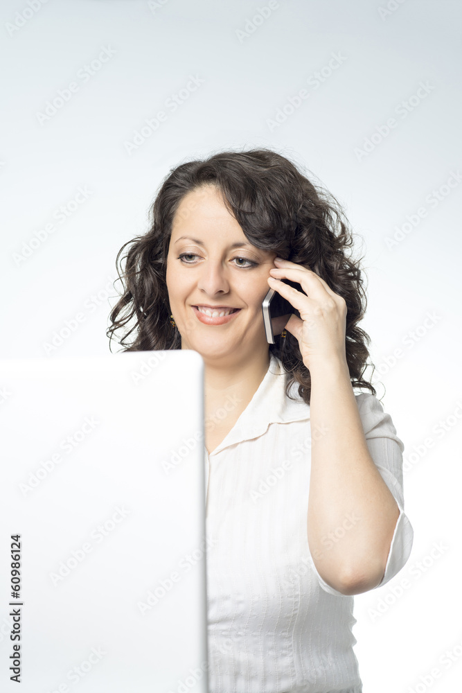 Young woman in front of laptop talking on the phone Young woman in front of laptop talking on the phone