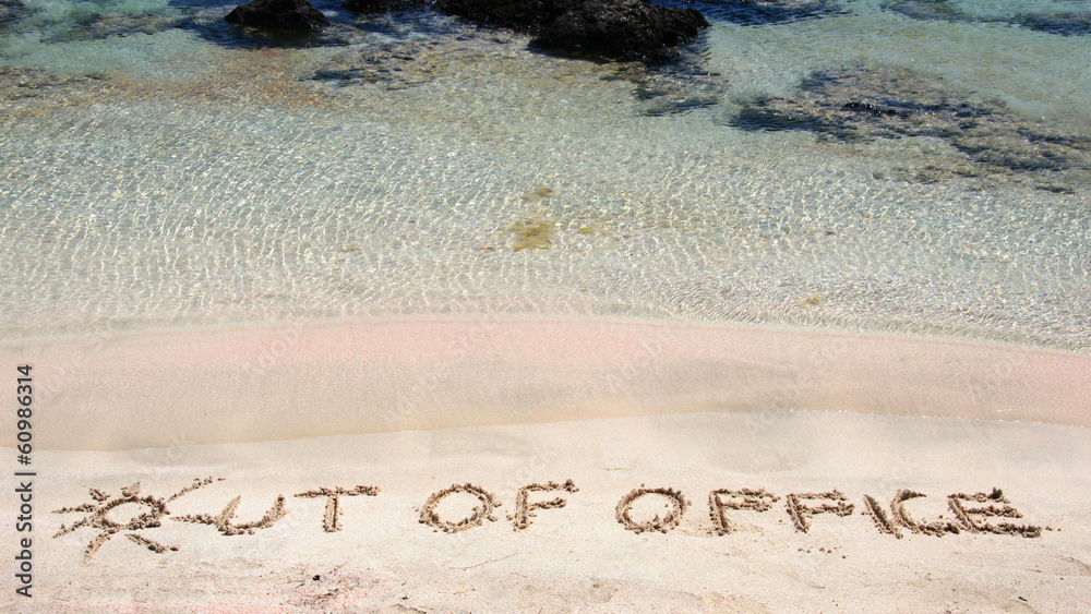 OUT OF OFFICE written on sand on a beautiful beach