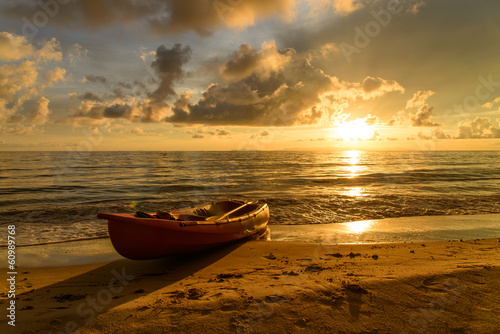 Onshore kayak boat with sunset in the background