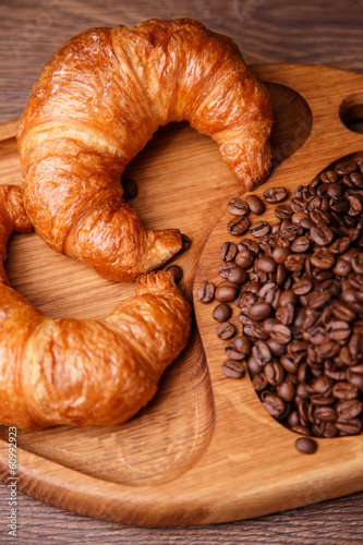 Croissants and coffee beans on a wooden board