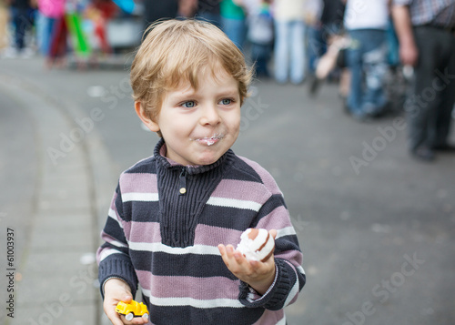 Little boy of three years eating at a funfair, outdoors
