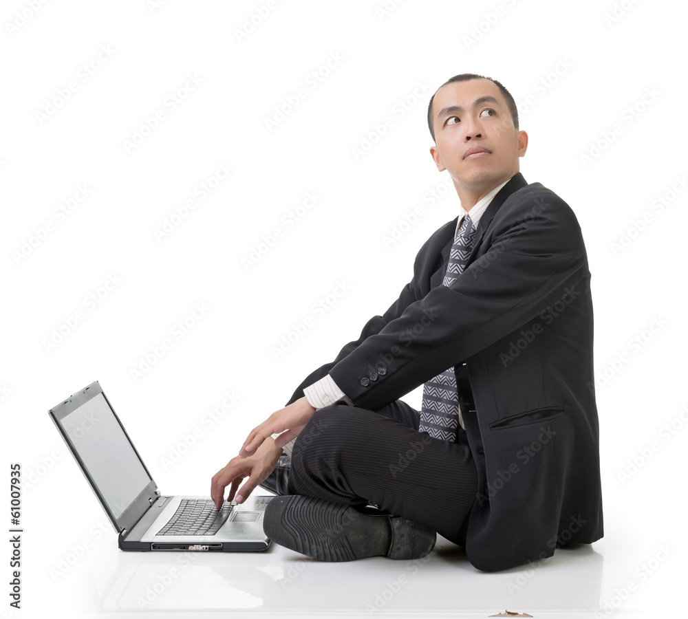 Asian businessman using laptop on ground looking back Asian businessman using laptop on ground looking back